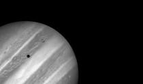 Jupiters volcanic moon Io passing above the turbulent clouds of the giant planet 