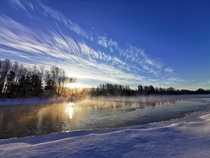 Painted clouds and blue winter sky over steaming river in Qubec 