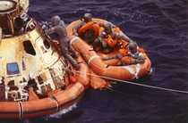 Pararescueman Lt Clancy Hatleberg closes the Apollo  spacecraft hatch as astronauts Neil Armstrong Michael Collins and Buzz Aldrin Jr await helicopter pickup from their life raft They splashed down on July    miles southwest of Hawaii after a successful l