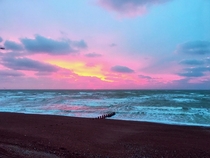 Pink sky by raging waves   before full cloud  and rain  beautiful omen
