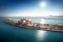 Resort constructed on a man-made island with sun shining through the structure in Dubai