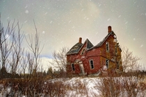 Rural decay of a century farmhouse in a winter snow storm Shelburn Ontario Canada Photo by Ron Clifford 