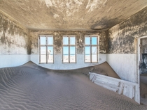 Sand devours a building in the abandoned diamond-mining town of Pomona on the Namibian coast 
