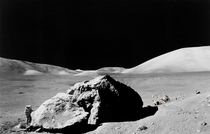 Scientist-astronaut Harrison H Schmitt standing next to a huge split lunar boulder during the third Apollo  extravehicular activity 