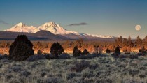 Sister mountains with the full moon setting at sunrise west of Bend Oregon 
