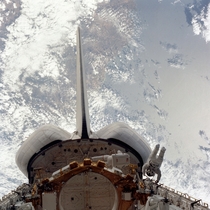 STS- mission specialists Donald H Peterson on the right side of the picture and Story Musgrave back to camera inside the cargo bay evaluate the handrail system on the Space Shuttle Challenger during an EVA 