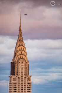 The Chrysler Building in NYC at sunset as a plane flies past 