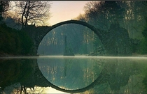 The Devils bridge is a th century structure in Kromlau Germany that was designed to make a perfect circle with its reflection in the water below