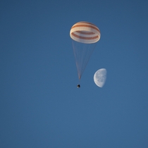 The Expedition  Soyuz parachuting down to Earth with the Moon in the background 