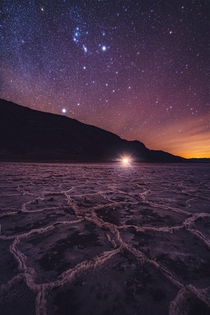 This is Badwater Basin in Death Valley As Orion rises overhead the distant glow from Las Vegas illuminates the salt flats 