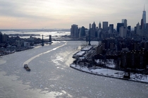 Vessels on the East rivers maneuver through floating ice sheets as the Stature of Liberty stands in a frozen harbor NY 