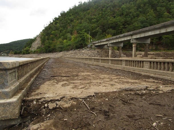  Every few years the waters of Chilhowee Lake are drained in order for Chilhowee Dam to be safely inspected During this time the eerie remains of a company town abandoned in  are visible including Abrams Creek Bridgeshown here The new bridge can be seen t