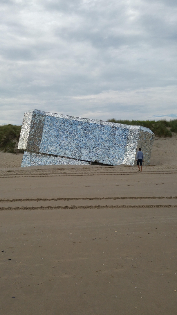 A bunker on the beachfront of Normandy covered in shards of mirrors 