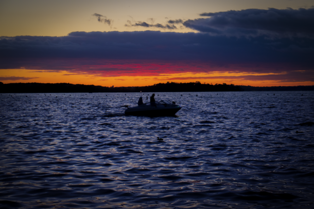 A couple boaters enjoying a pink-orange sunset 
