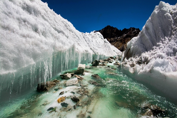 A river rushes it way through Ice during Kalindi Khal Trek Uttarakhand India 