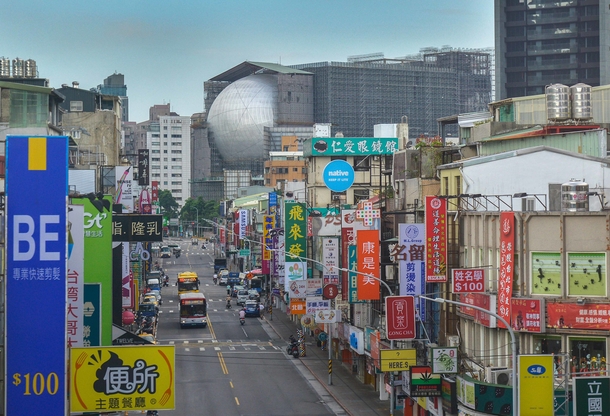 A street with many signs in Taipei Taiwan with the Taipei Performing Arts Center in the background 