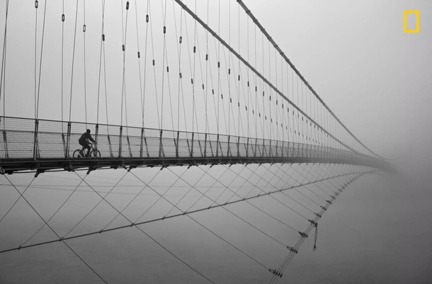 A traveler riding across Ram Jhula bridge in India 