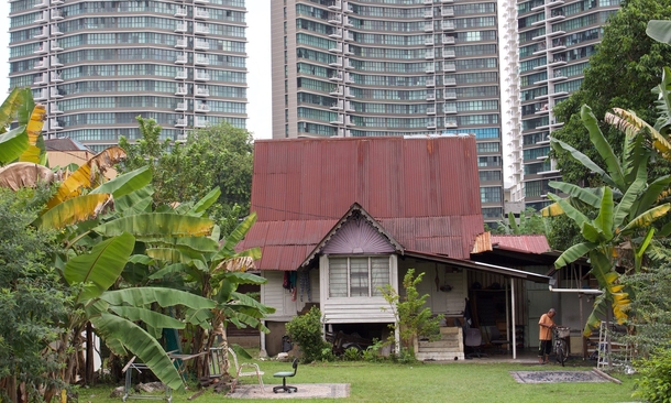 A village in the city - a traditional Malay house in Kampong Bharu New Village overshadowed by high-rise apartment towers in Kuala Lumpur Malaysia 