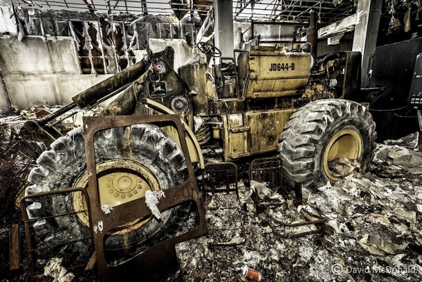 Abandoned front end loader rusting away inside a burnt out heavy equipment repair shop