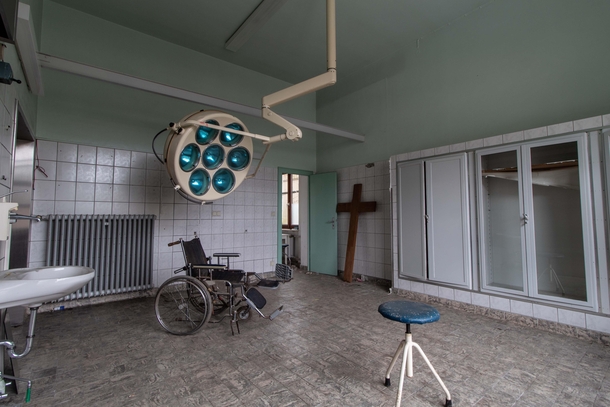 Abandoned operating theatre with wheelchair and surgical lamp 