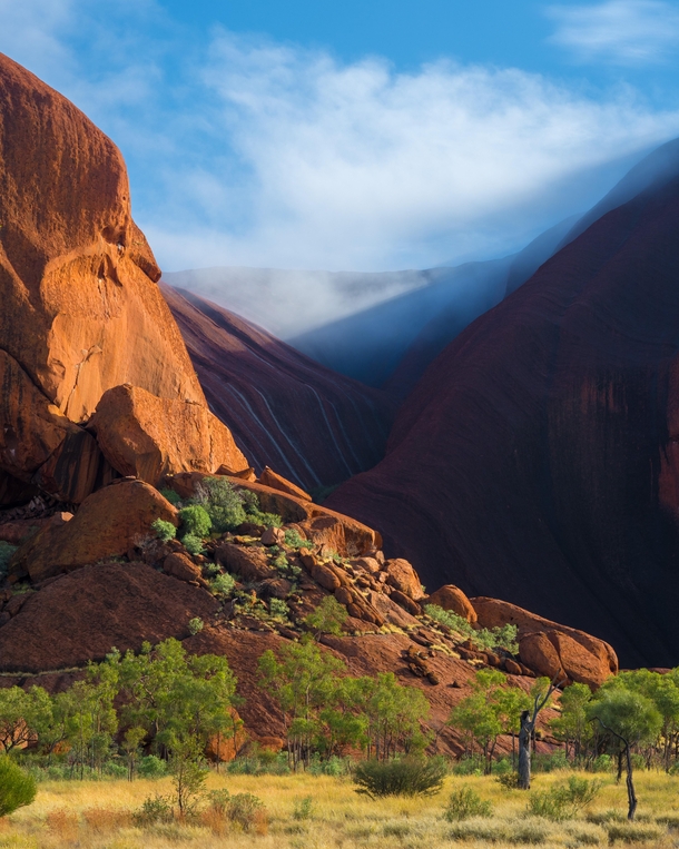 After days of heavy rain the moisture on the rock evaporated into clouds under the morning sun - Uluru NT Australia 