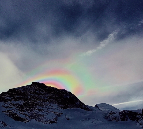 Airborne snow particles reflect the setting sun behind the Alphubel summit in Switzerland forming a spectacular snowbow OC   