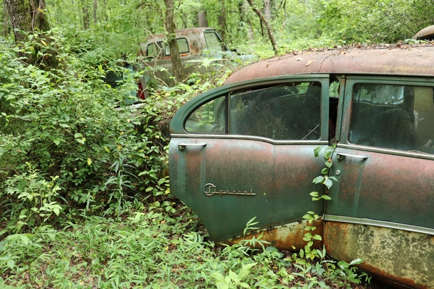 An abandoned car in an old junkyard looks like its still waiting for someone to get in 