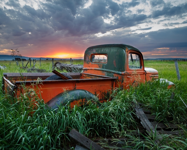 An abandoned truck watches a sunset in an Idaho field