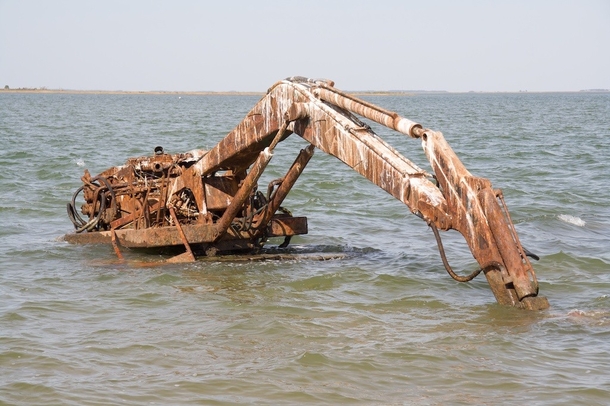 An excavator left to rust in the water near an abandoned island in Chesapeake Bay Photo by uxarvox 
