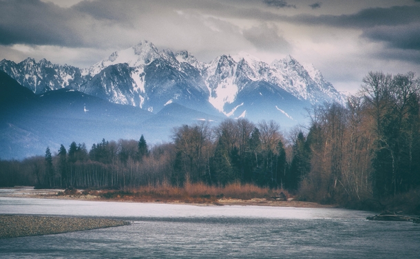 At the riverbend at The Cascade Mountains rise over the Skykomish River in Washington State US by Montana Roots 