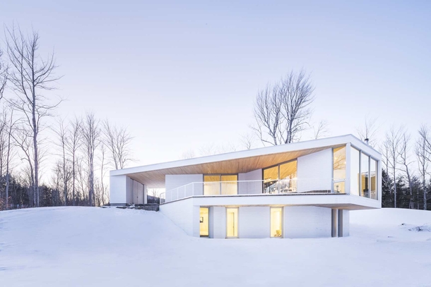 Bright white home blends with snowy landscape in Quebec Canada by MU Architecture Photo Ulysse Lemerise Bouchard 