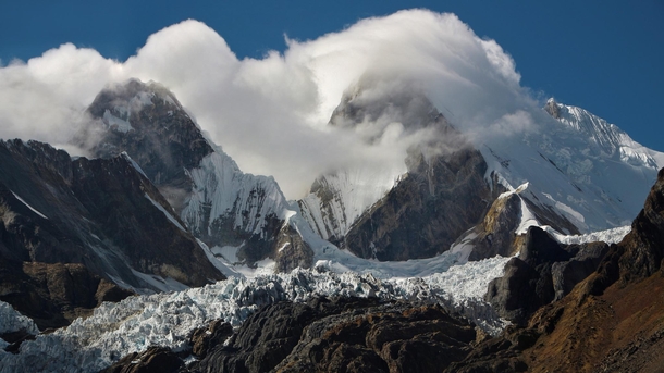 clouds taking over the mountains towering over the glacier in Cordillera Huayhuash Peru 