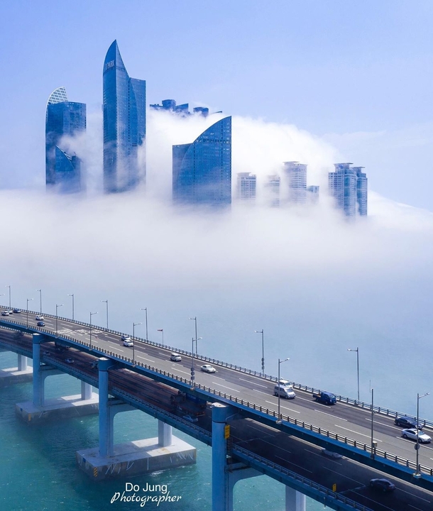 Double-decked Gwangan Bridge passing by a cluster of residential skyscrapers engulfed in sea fog Busan South Korea 