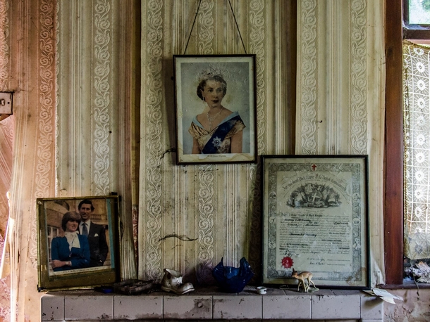 Fireplace of an abandoned home in Northern Ireland with framed pictures of the Royal family 