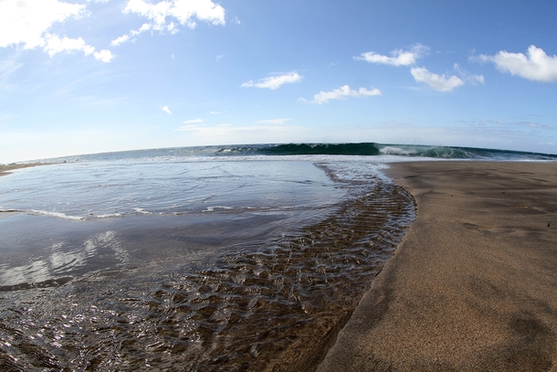 Fresh water trickling into the Pacific ocean on a secluded beach in Kauai Hawaii 