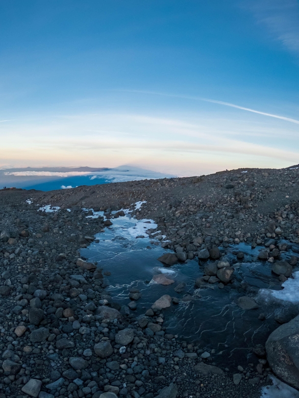 Frozen stream on Mt Adams with the sunrise shadow of the mountain in the distance 