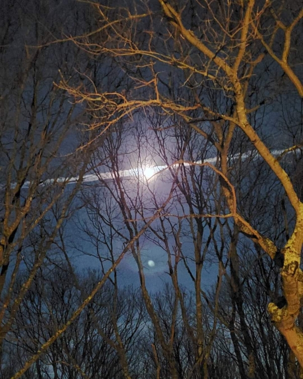 Full Snow Moon with a jet contrail and orb of light Perfect timing East Hampton New York