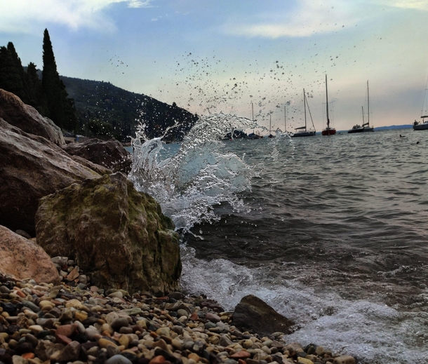 Glass-like wave after crushing into rocks on Garda Lake northern Italy 