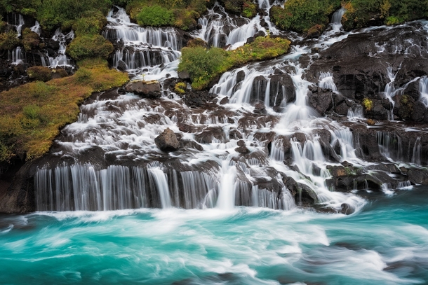 Hraunfossar Borgarfjrur western Iceland is a series of waterfalls formed by rivulets streaming over a distance of about  metres out of the Hallmundarhraun a lava field which flowed from an eruption of one of the volcanoes lying under the glacier Langjkull