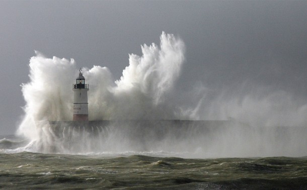 Huge waves break over the lighthouse on Newhaven Harbour as the country braces itself for more gales and rain Newhaven East Sussex England 