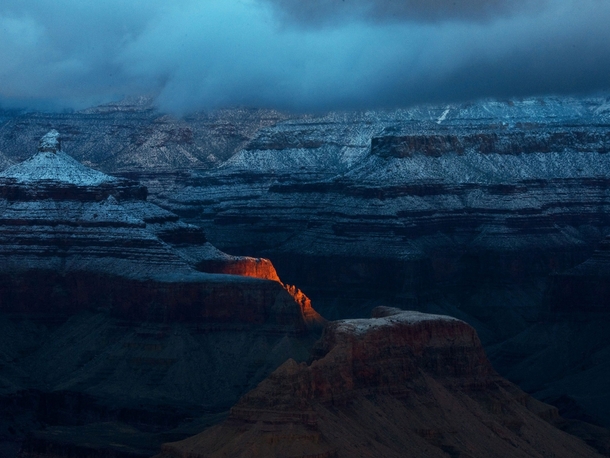 I hiked along the rim awaiting the arrival of the sun The skies were still overcast but a small break in the clouds allowed a single ray of sunlight to shine through illuminating a small portion of the butte below - Grand Canyon National Park Arizona  Pho