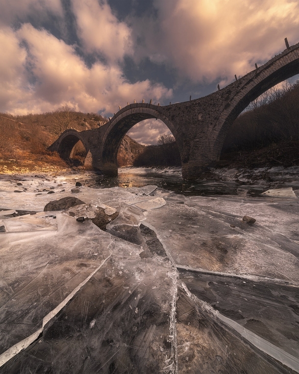 Icy river under the arches of Kalogeriko bridge Zagori Greece
