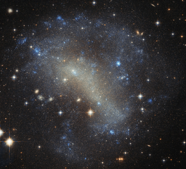 Irregular galaxy IC  roughly  million light-years away with milky way stars and galaxies blazing brightly in front of and behind respectfully making for a wonderful snapshot of the universe image credit Hubble