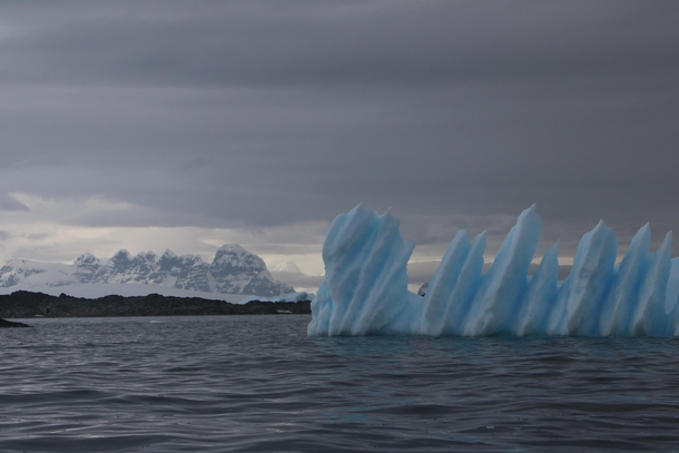 Jagged mountains stand behind a jagged iceberg Antarctic Peninsula 