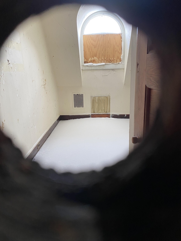 Looking through the peephole of this abandoned building you can see snow has gotten in and covered the floor