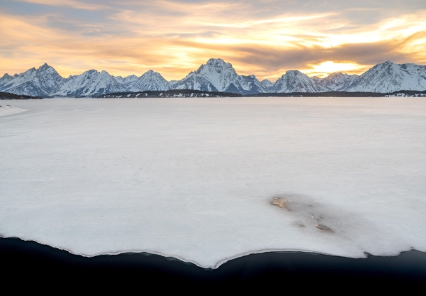 Mount Moran and the Teton Range in the background with a mostly frozen Jackson Lake in the foreground Grand Teton on the far left 