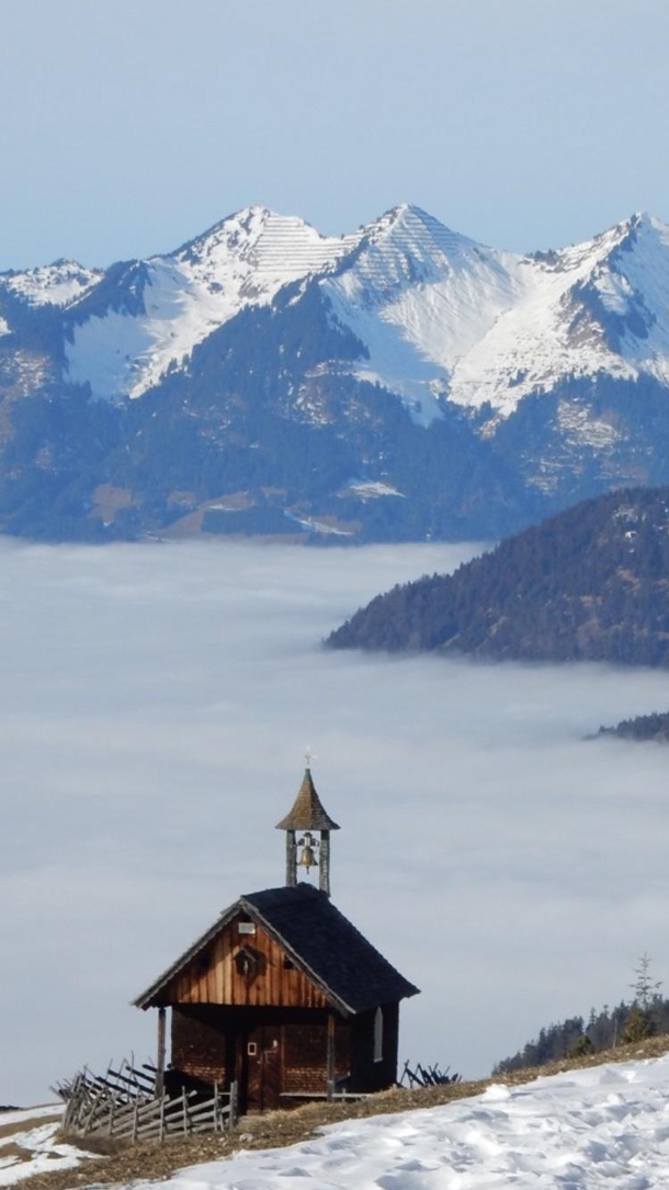 Old church looks over misty valley Montafon Austria 