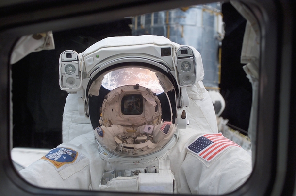 Orbiting high above Earth NASA Astronaut John M Grunsfeld peers into the crew cabin of the Space Shuttle Columbia during the first STS- extravehicular activity EVA- on March   The photo was snapped with a digital still camera by a crewmate on shuttles aft