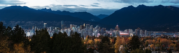 Panorama of the Vancouver skyline surrounded by mountains and autumn coloured trees 