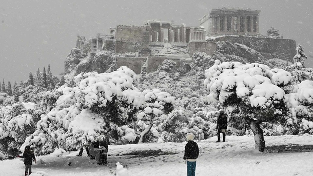 People enjoying the snow in Greece with a beautiful view at the Acropolis